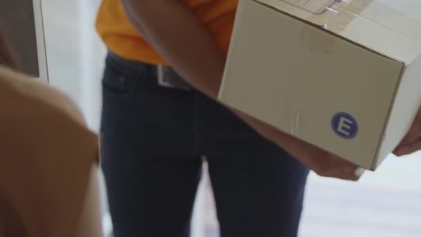 Young delivery Asian man holding a cardboard box while Asian young woman putting signature in the tablet. - Filmmaterial, Video