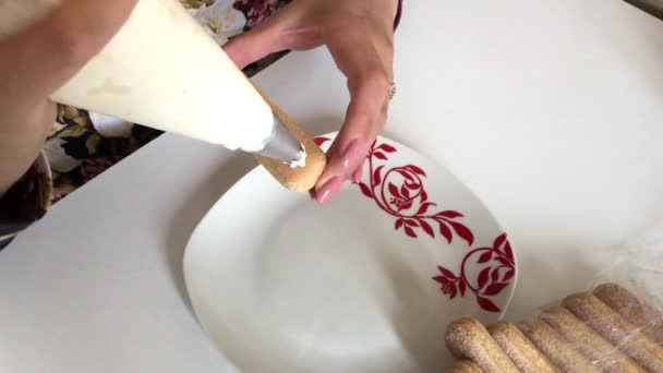 Woman spreads cream savoiardi cookies and puts on a plate. - Video
