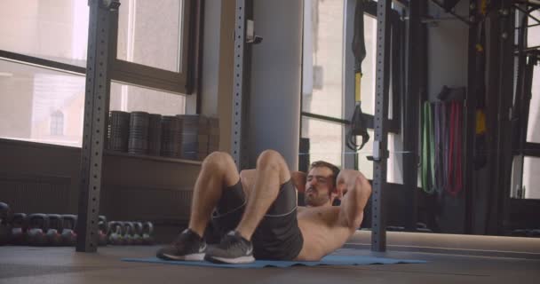 Κοντινό πλάνο από ημίγυμνος μυώδης όμορφος Καυκάσιος άνθρωπος ταλαντεύεται στο γυμναστήριο σε εσωτερικούς χώρους - Πλάνα, βίντεο