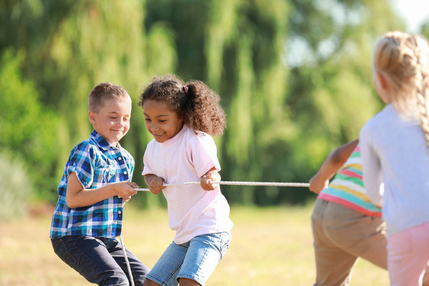Група маленьких дітей тягне мотузку в парку
 - Фото, зображення