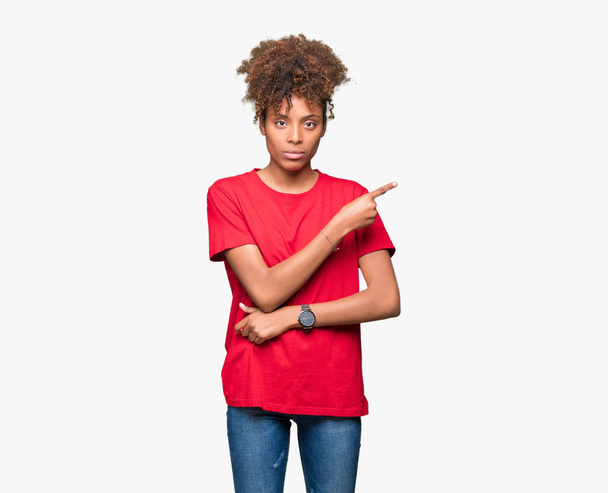 Beautiful young african american woman over isolated background Pointing with hand finger to the side showing advertisement, serious and calm face - Photo, Image