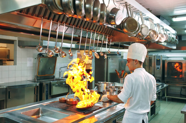 Modern kitchen. Cooks prepare meals on the stove in the kitchen of the restaurant or hotel. The fire in the kitchen. - Foto, Bild