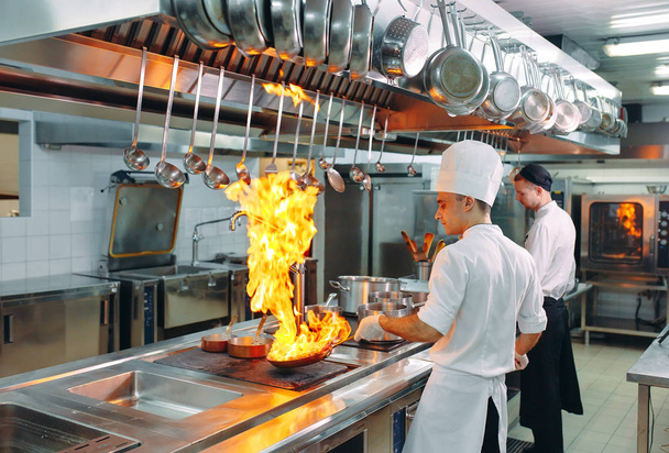 Modern kitchen. Cooks prepare meals on the stove in the kitchen of the restaurant or hotel. The fire in the kitchen. - Valokuva, kuva