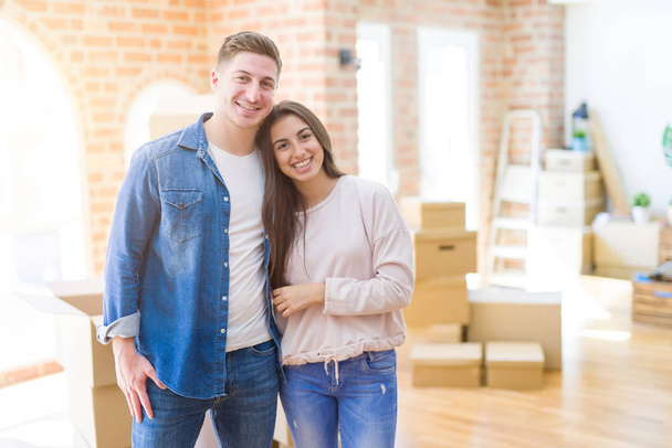 Beautiful young couple moving to a new house with a happy and cool smile on face. Lucky person. - Photo, Image