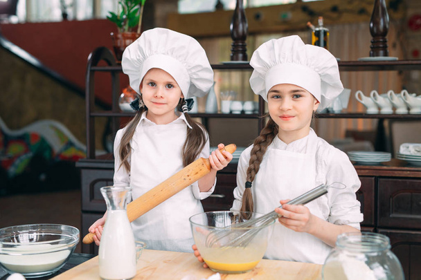 funny girls kids are preparing the dough in the kitchen. - Foto, Imagen