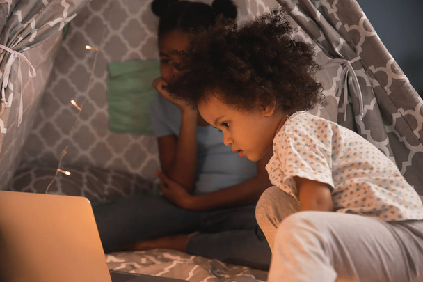 Carino afro-americano sorelle con computer portatile guardando cartoni animati in hovel
 - Foto, immagini