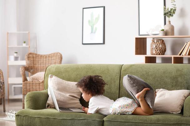 Симпатичні афро-американських дівчина з ноутбуком дивляться мультфільми в домашніх умовах - Фото, зображення