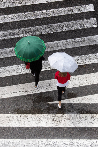 Scena di due donne con ombrello di moda che attraversano il marciapiede. Vista dall'alto
 - Foto, immagini