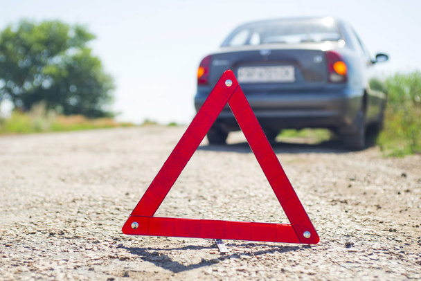 Czerwony trójkąt ostrzegawczy z rozkładanym samochodem. Samochód z podziałem wzdłuż drogi - Zdjęcie, obraz