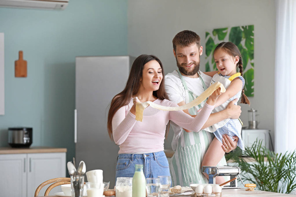 Young family cooking together in kitchen - Foto, afbeelding