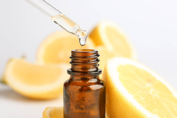 Citrus essential oil dripping from pipette into bottle on white background - Photo, Image