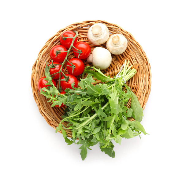 Płyta wiklinowa z arugula, grzyby i pomidor na białym tle - Zdjęcie, obraz