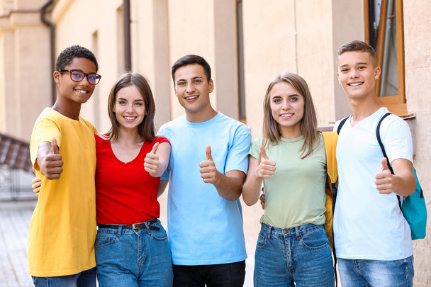 Portrait of young students showing thumb-up outdoors - Photo, Image
