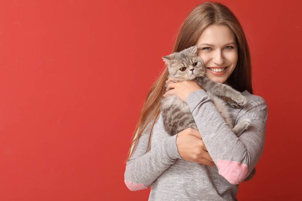 Beautiful young woman with cute cat on color background - Photo, Image