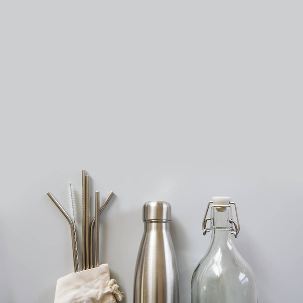 Eco natural metallic straws, bottle with cotton bag on grey. Sustainable lifestyle concept. Zero waste, plastic free. Pollution environment. - Фото, зображення