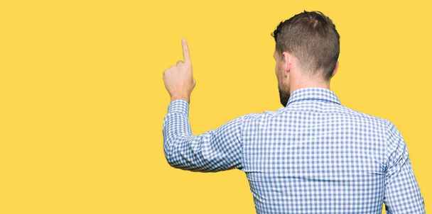 Handsome business man with blue eyes Posing backwards pointing behind with finger hand - Photo, Image