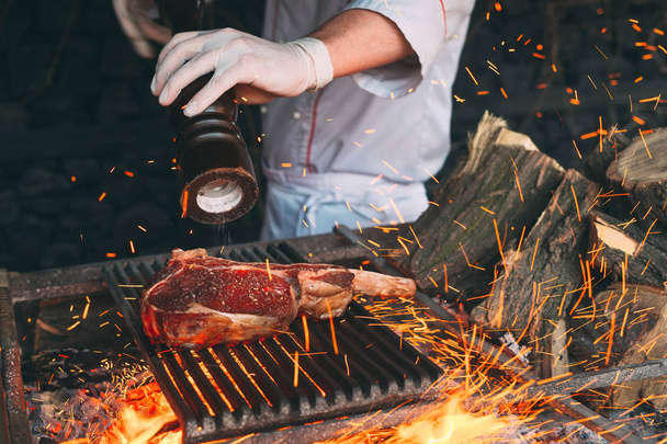 Chef Cooking steak. Cook turns the meat on the fire. - Фото, изображение