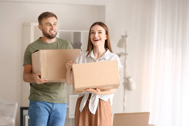 Feliz pareja joven con cajas de mudanza en su nueva casa
 - Foto, imagen