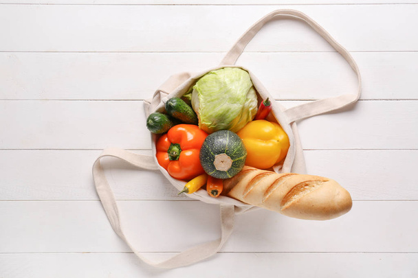 Эко сумка с продуктами на белом деревянном фоне
 - Фото, изображение
