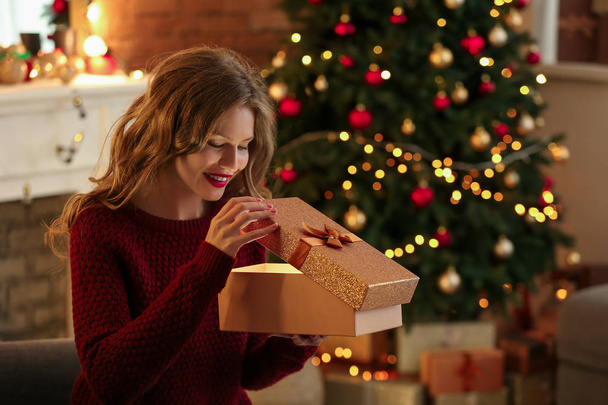 Boldog fiatal nő nyitó karácsonyi ajándék otthon - Fotó, kép