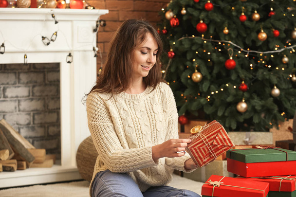 Щаслива молода жінка з різдвяними подарунками вдома
 - Фото, зображення