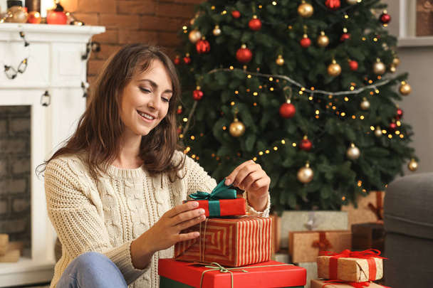 Onnellinen nuori nainen avaamalla joululahjoja kotona
 - Valokuva, kuva