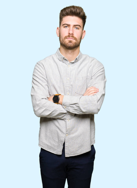 Jonge knappe man draagt casual shirt sceptisch en nerveus, afkeurende uitdrukking op gezicht met gekruiste armen. negatieve persoon. - Foto, afbeelding