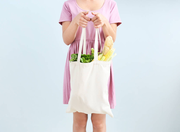 Γυναίκα που κατέχουν Eco τσάντα με προϊόντα σε φως φόντο - Φωτογραφία, εικόνα