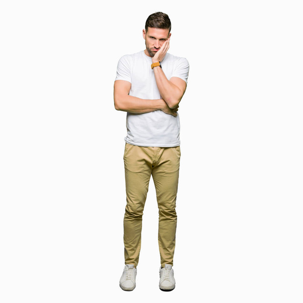 Handsome man wearing casual white t-shirt thinking looking tired and bored with depression problems with crossed arms. - 写真・画像