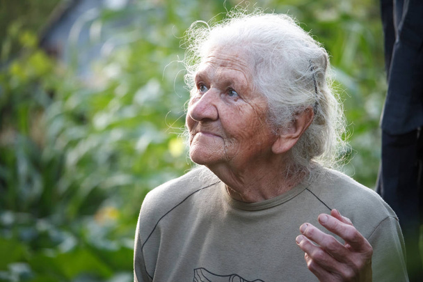 Retrato de cerca de una anciana con el pelo gris sonriendo y mirando hacia arriba, cara en arrugas profundas, enfoque selectivo
 - Foto, Imagen
