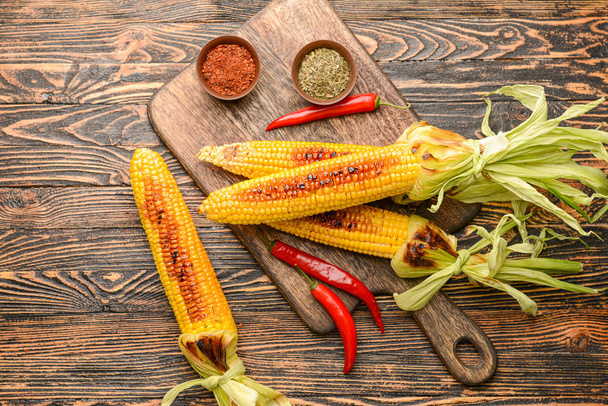 Composition with tasty grilled corn cobs on wooden background - Fotografie, Obrázek