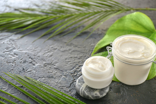 Jars of natural cream and tropical leaf on dark background - Foto, afbeelding
