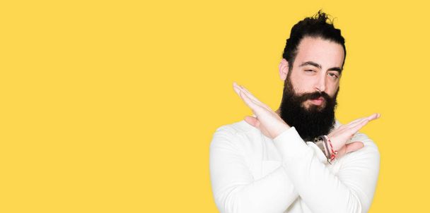 Jonge hipster man met lang haar en baard dragen sportieve Sweatshirt afwijzing expressie kruising armen doen negatieve teken, boos gezicht - Foto, afbeelding