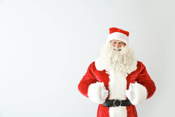 Porträt des Weihnachtsmannes mit Daumen nach oben auf hellem Hintergrund - Foto, Bild