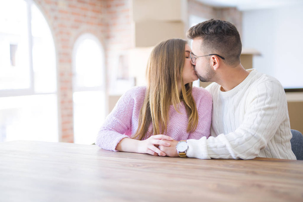 Young beautiful couple sitting on the table at home, hugging in  - Photo, Image
