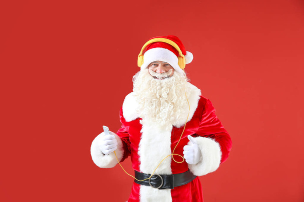 Portrait of cool Santa Claus listening to music on color background - Photo, Image