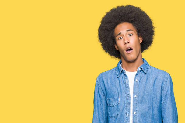 Jeune homme afro-américain aux cheveux afro En état de choc face, l'air sceptique et sarcastique, surpris avec la bouche ouverte
 - Photo, image