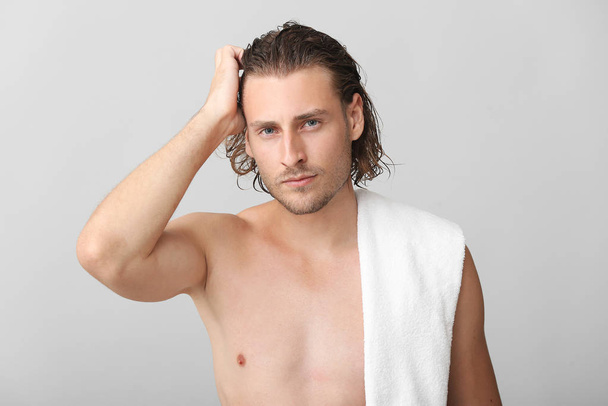 Hombre joven guapo después de lavar el cabello contra el fondo gris
 - Foto, imagen
