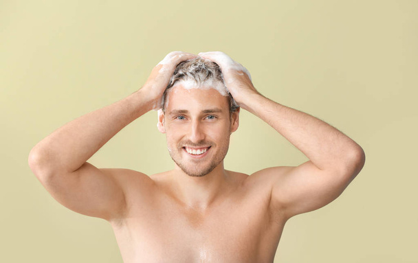 Jóképű fiatalember mosás haj ellen színes háttér - Fotó, kép