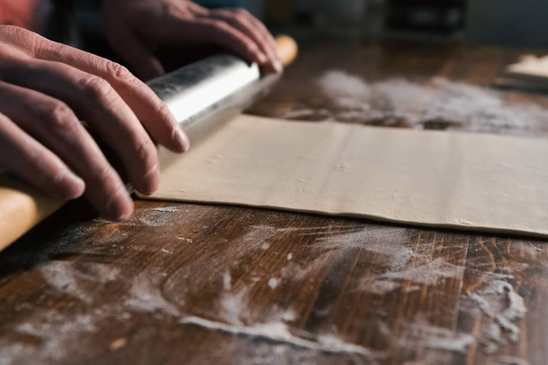 rolling out the dough with rolling pin on the table. - Foto, Imagen