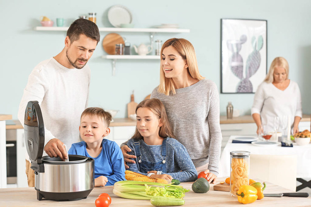 Família feliz usando fogão multi moderno na cozinha
 - Foto, Imagem