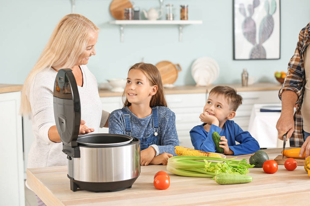 Бабушка и маленькие дети с современной мульти-плита на кухне
 - Фото, изображение