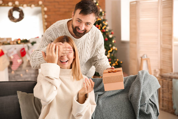 Happy man giving his wife Christmas present at home - Photo, Image