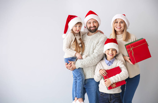 Happy family with Christmas gifts on light background - Foto, Imagen