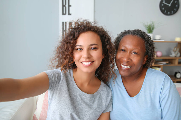 Πορτραίτο της αφρικανικής-Αμερικάνικης γυναίκας με την κόρη της να παίρνει selfie στο σπίτι - Φωτογραφία, εικόνα