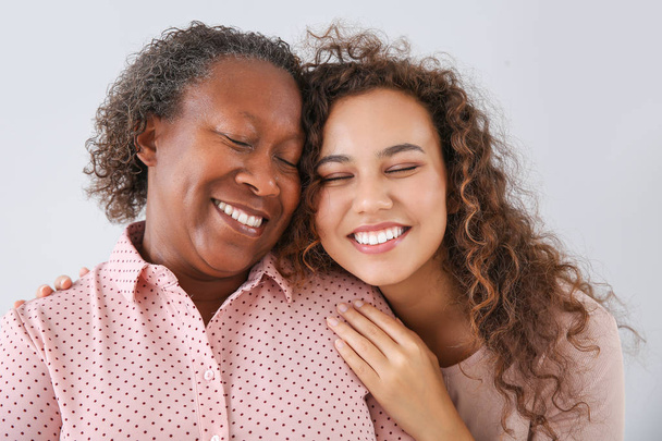 Portret van Afro-Amerikaanse vrouw met haar dochter op lichte achtergrond - Foto, afbeelding