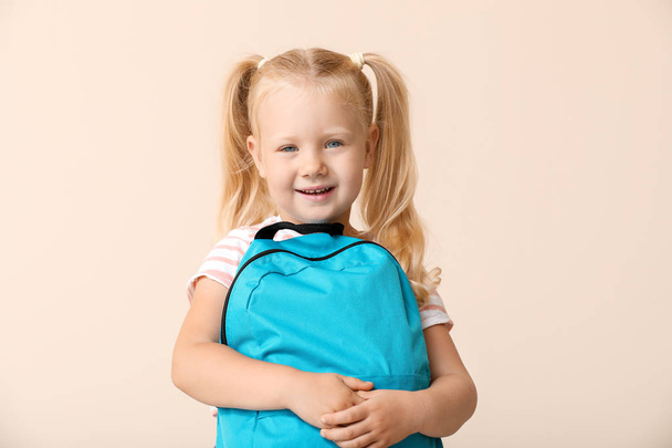 Cute little schoolgirl with backpack on light background - Photo, Image