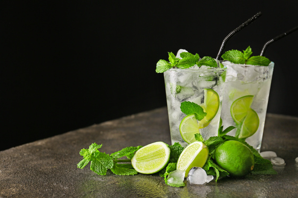 Glasses of fresh mojito on table against dark background - Photo, image