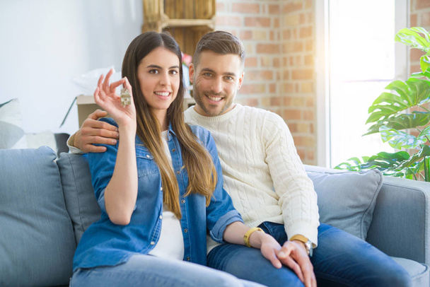 Young couple moving to a new home, hugging in love showing keys of new apartment smiling very happy - Photo, image
