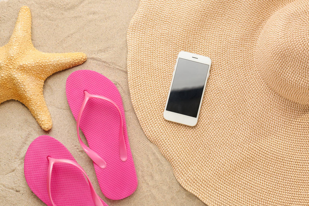 砂浜で携帯電話、帽子、ヒトデとフリップフロップ - 写真・画像